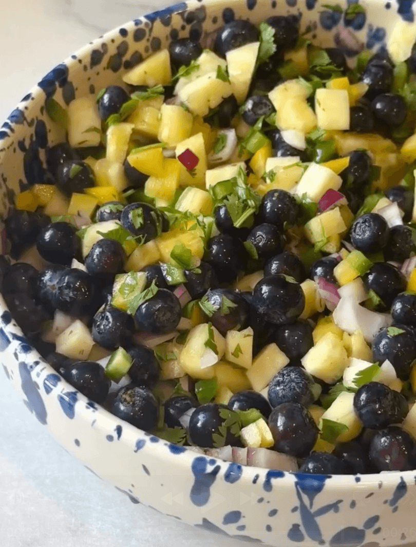 side view of blueberry pineapple salsa in a blue and white bowl