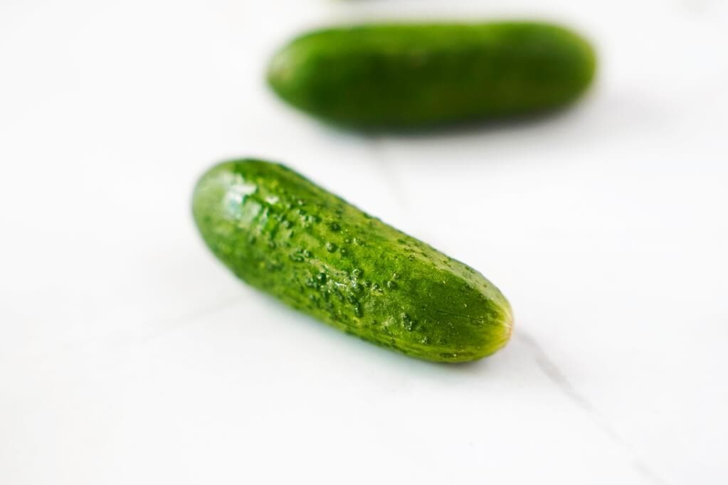 Close up of a baby cucumber on white counter