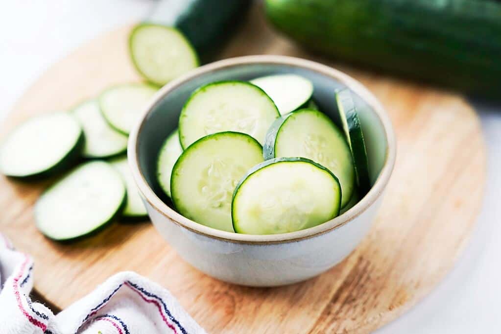 cucumber rounds in a bowl on top of a wood cutting board