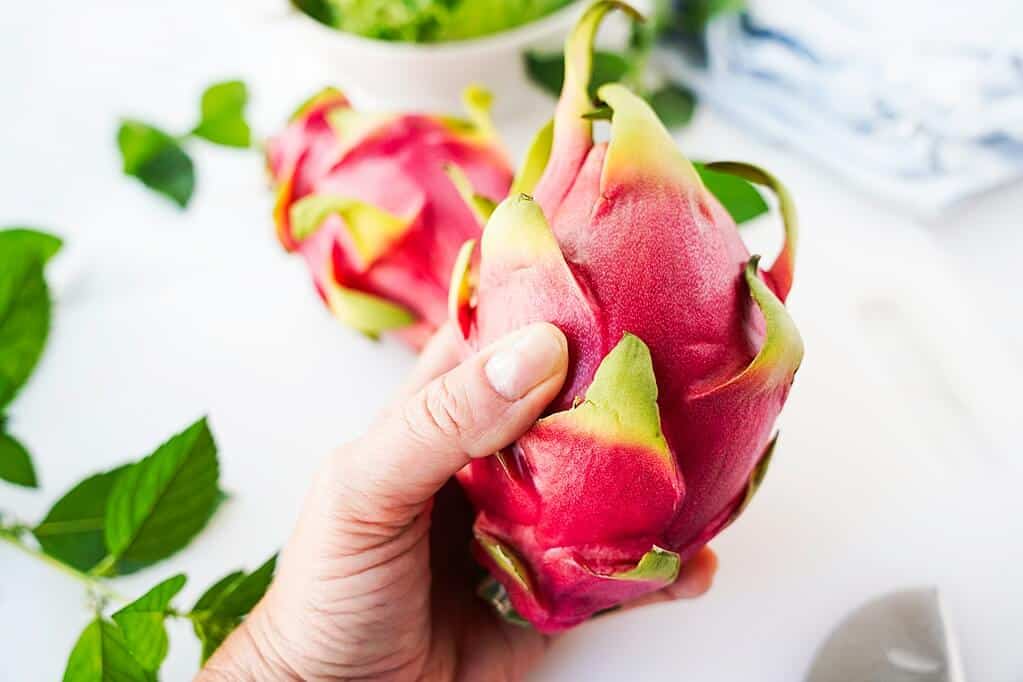 Putting pressure on the dragon fruit with thumb