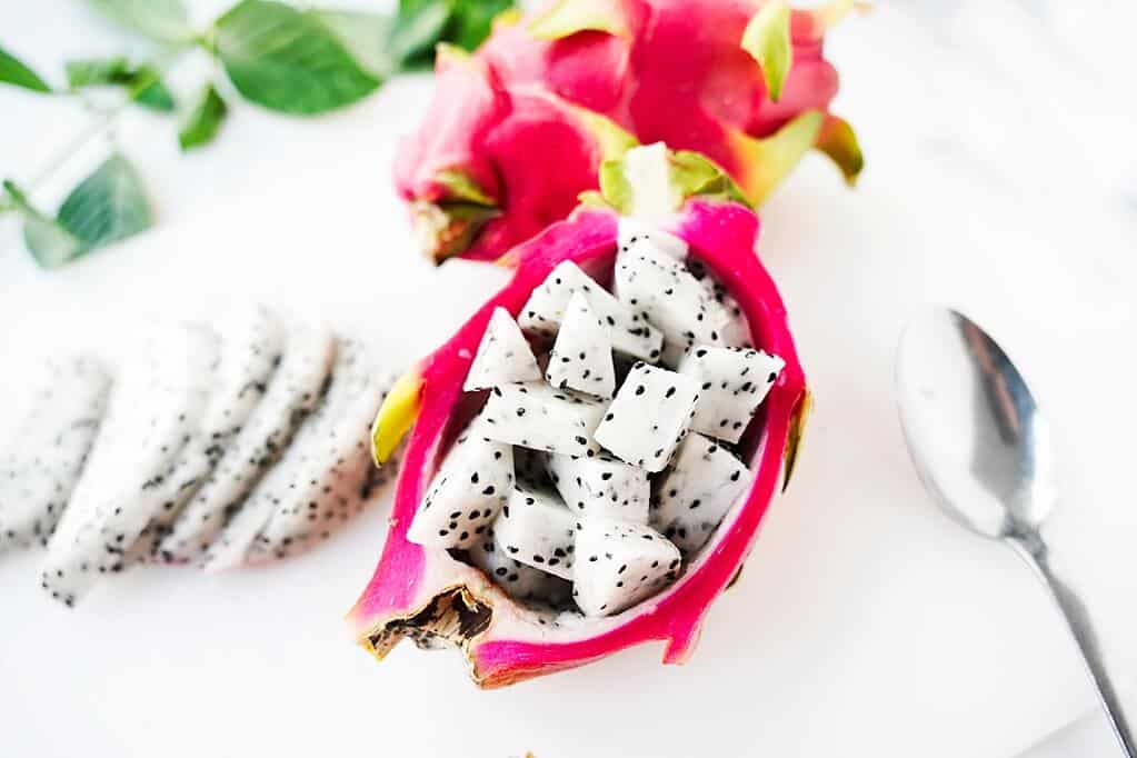 Cubed dgraon fruit flesh in skin of dragon fruit with half moons next to it