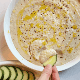 Dipping a cucumber into the white bean artichoke dip