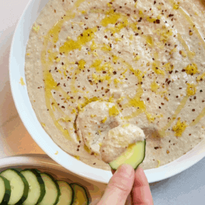 Dipping a cucumber into the white bean artichoke dip