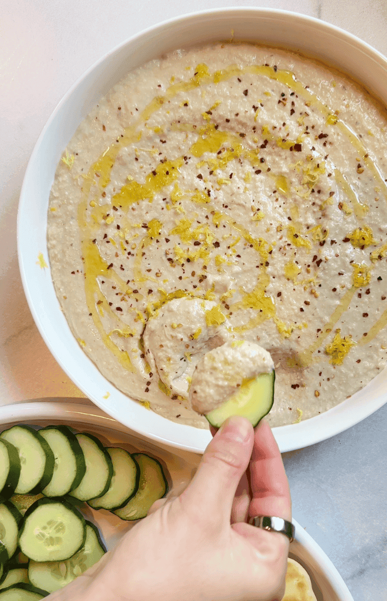 Dipping a cucumber into the white bean artichoke dip