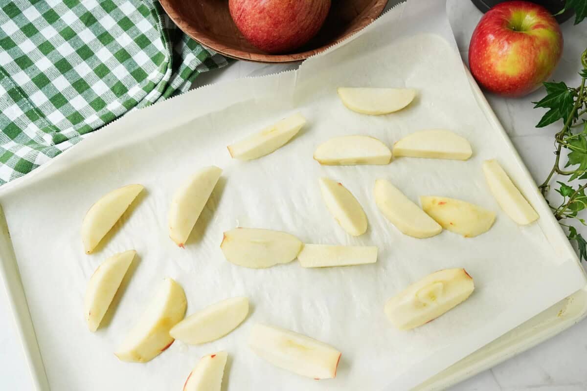 Slices of apples on a parchment lined baking sheet for flash freezing