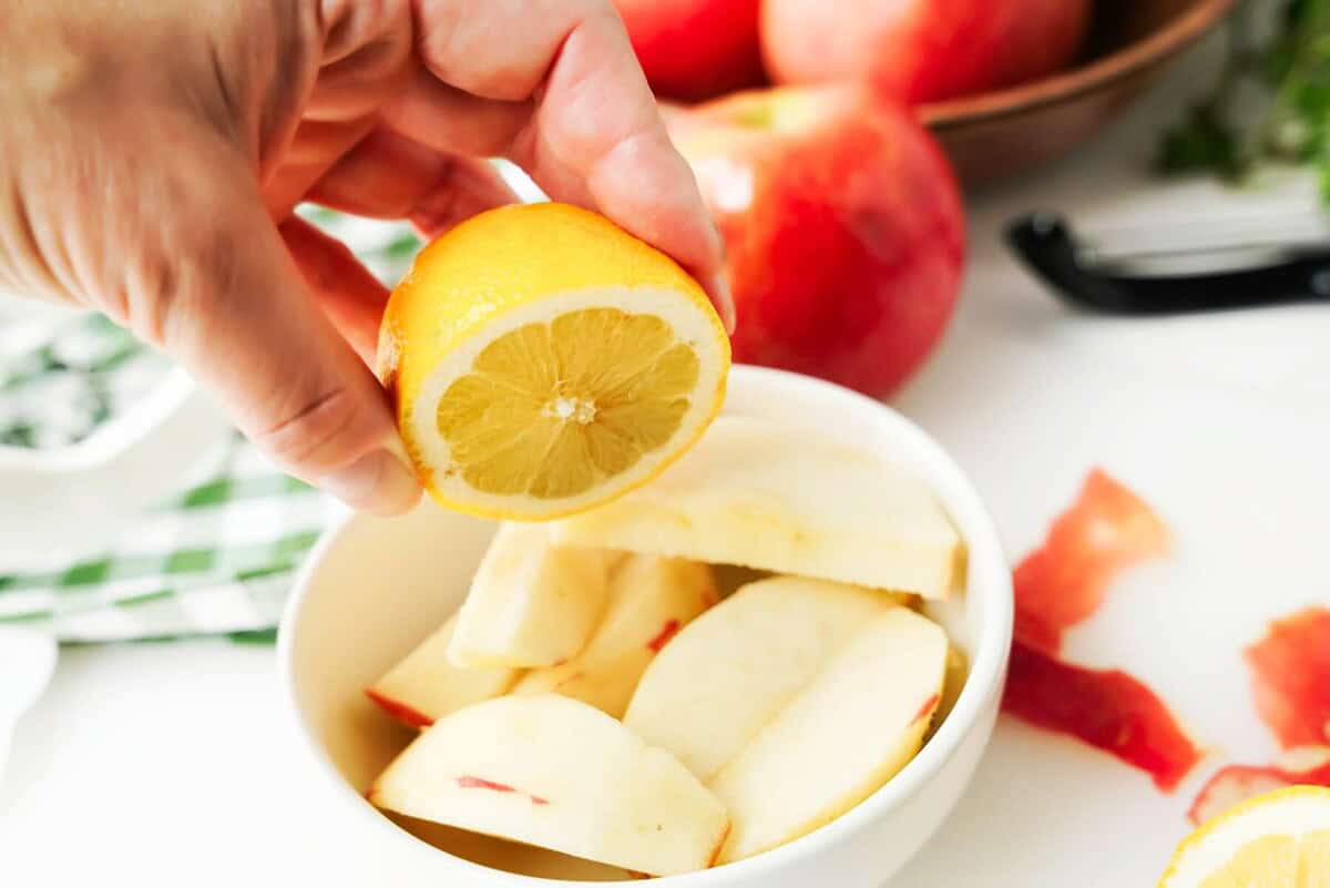 Squeezing lemon juice on a bowl of apple slices
