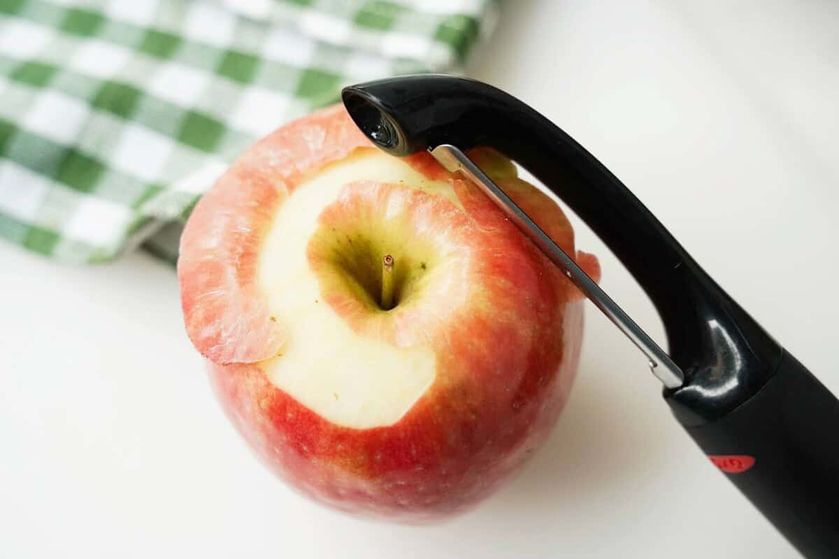 Using a peeler, peeling an apple at the top