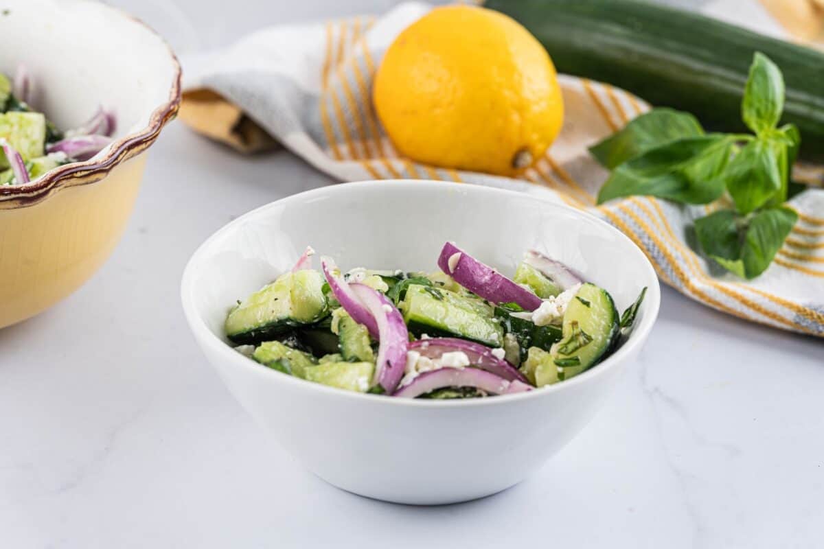 A serving of smashed cucumber salad in a white bowl.