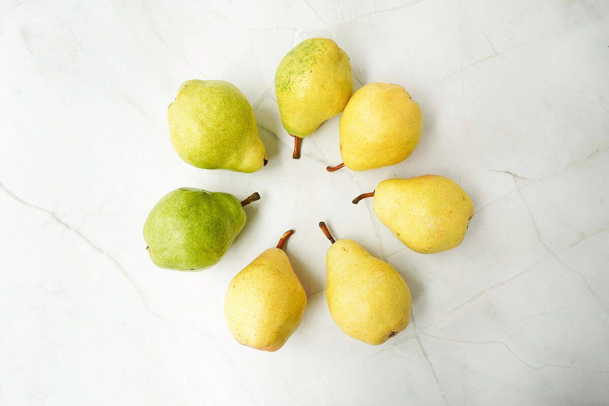 Bartlett pears from green to yellow in a circle on a marble background