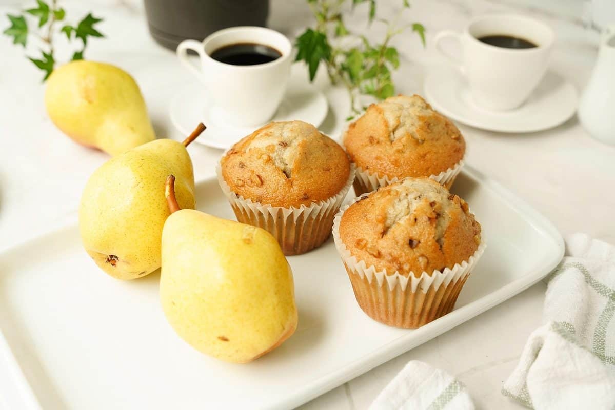 Pear muffins on a serving plate with deep yellow pears that are spotted