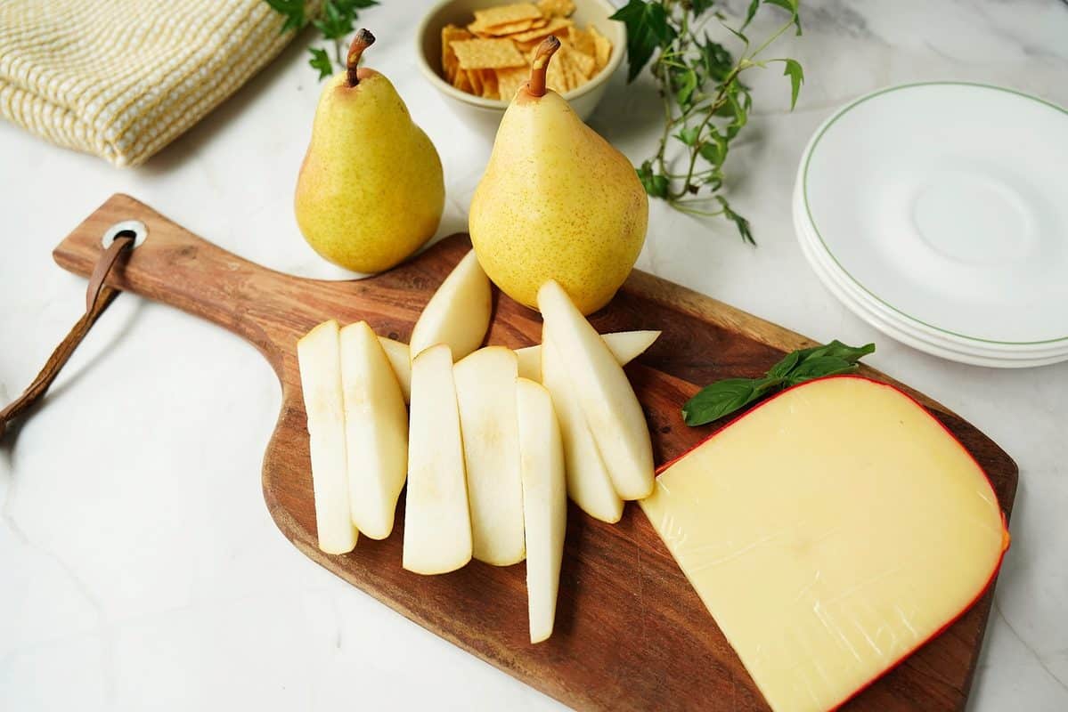 yellow pear sliced served with cheese and crackers on a cutting board