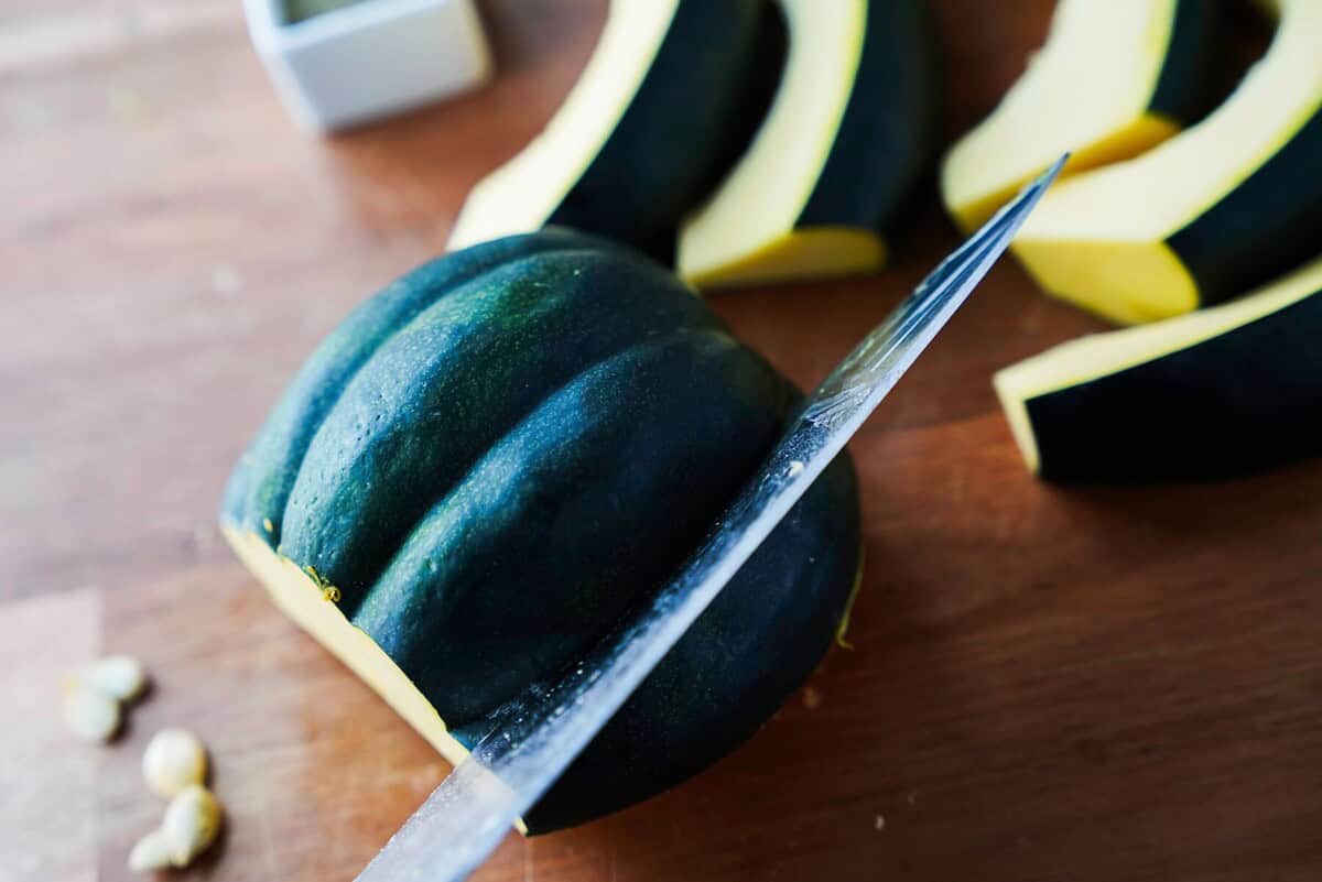 Knife running through the ridges of an acorn squash