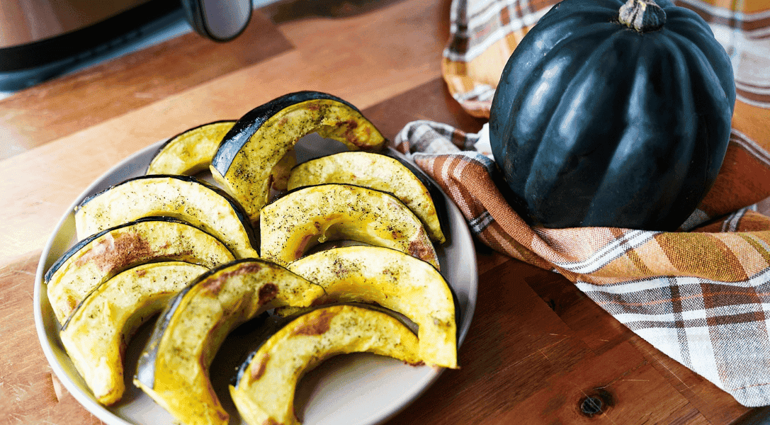 close up of air fryer squash pieces with whole acorn squash to the right