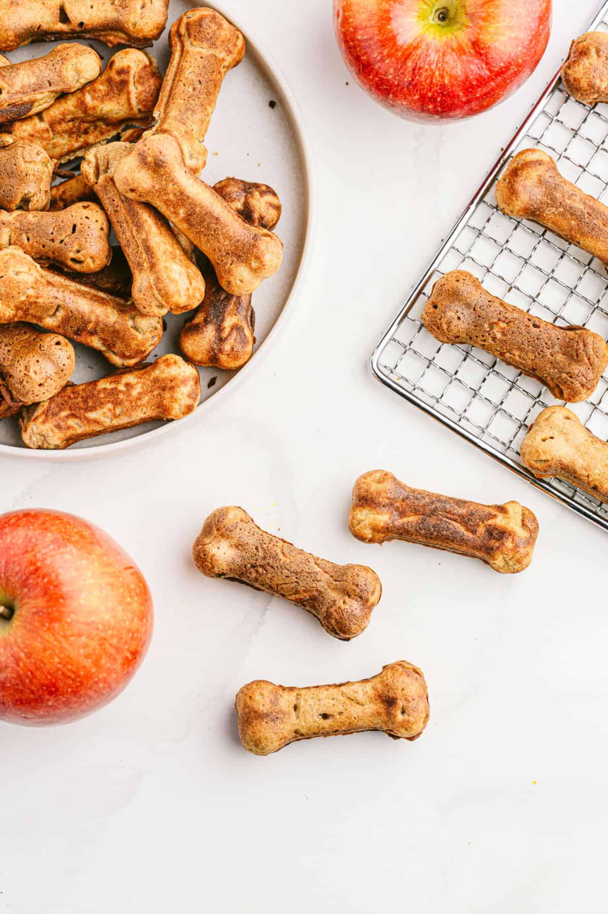Vertical view of apple & bacon dog treats on a cooling rack and treats on a plate
