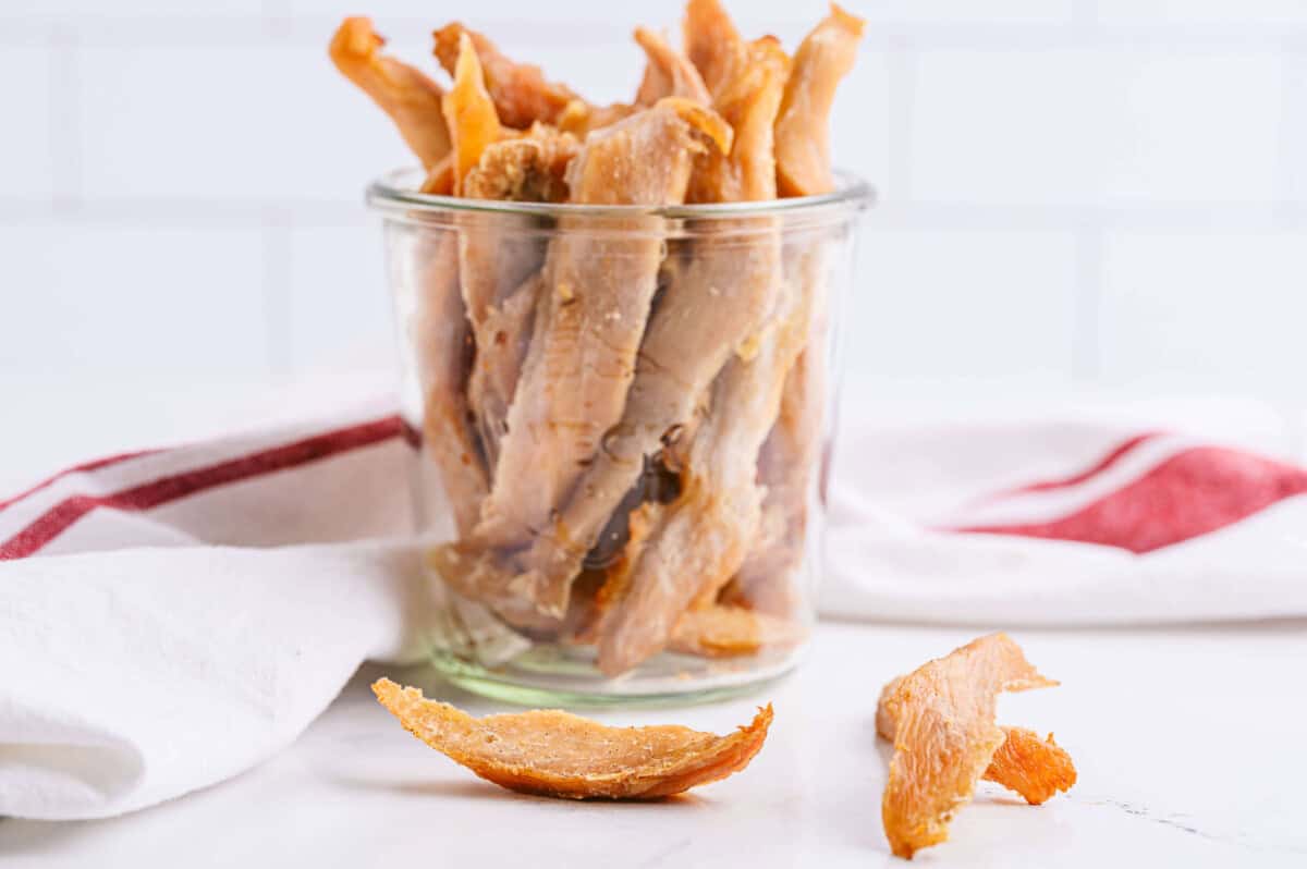 Pear Chicken Jerky Dog Treats in mason jar with a few pieces on the counter