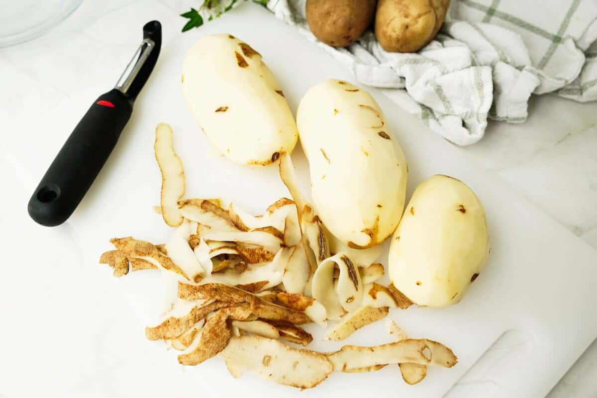 3 peeled potatoes on a cutting board
