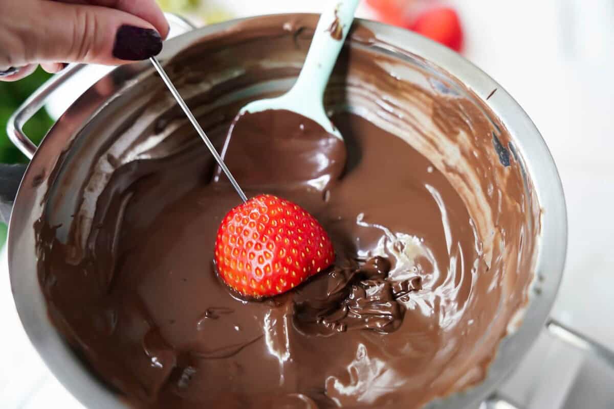strawberry getting dipped in melted chocolate