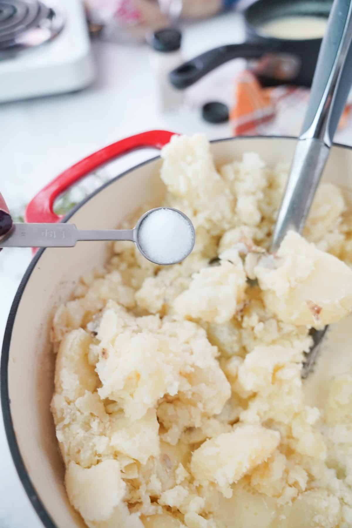 Salt added to mashed potatoes in a large pot