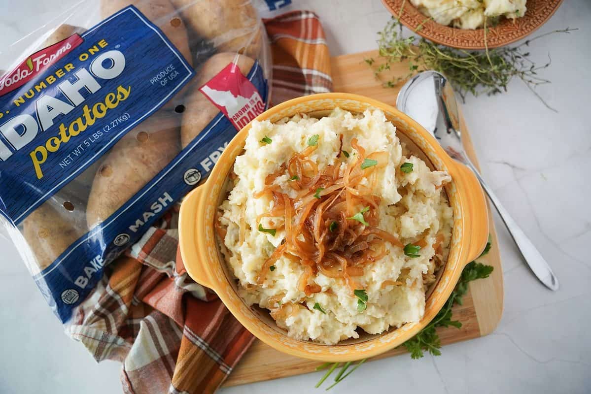 French onion mashed potatoes in a bowl with a bag of Wada Farms russet potatoes next to it